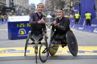 Marcel Hug, of Switzerland, left, winner of the Boston Marathon men's wheelchair division, left, and Eden Rainbow Cooper, of Britain, right, winner of the women's wheelchair division, display the trophy on the finish line Monday, April 15, 2024, in Boston. (AP Photo/Steven Senne)