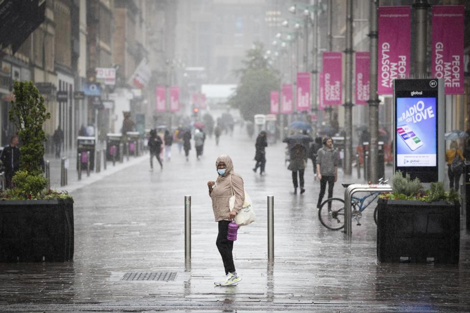 A file picture of a member of the public caught in heavy rain in Glasgow city centre: PA