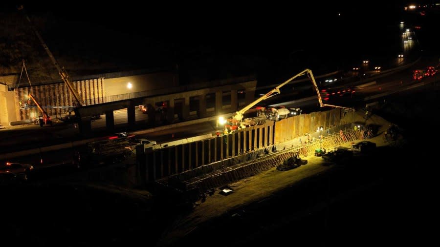 An aerial photo taken at night showing where crews are placing hundreds of tons of wet concrete for the foundation of the abutment, or bridge wall, next to the southbound lanes of US Highway 101 near Liberty Canyon Road in Agoura Hills, California, to build the Wallis Annenberg Wildlife Crossing. (Caltrans)