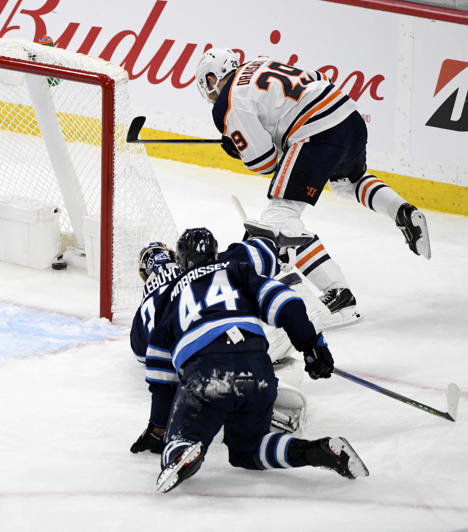 Edmonton Oilers' Leon Draisaitl (29) scores his second goal on Winnipeg Jets goaltender Connor Hellebuyck (37) as Josh Morrissey (44) defends during the first period of an NHL game against the Winnipeg Jets, in Winnipeg, Manitoba on Sunday, May 23, 2021. (Fred Greenslade/The Canadian Press via AP)