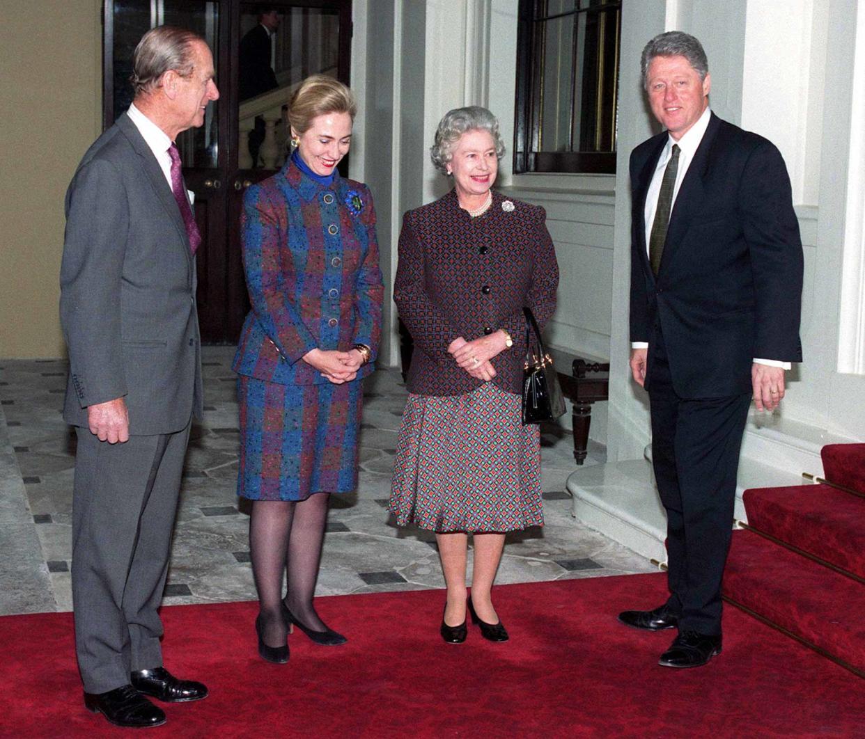 Queen Elizabeth II and Prince Philip with the Clintons, all in day clothes, Prince Philip cracking a joke and Hillary Clinton wearing a wide smile.