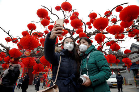 FILE PHOTO: Visitors wearing face masks against pollution take pictures of themselves at the temple fair at Ditan Park (the Temple of Earth) as the Lunar New Year of the Rooster is celebrated, in Beijing, China January 28, 2017. REUTERS/Damir Sagolj/File Photo