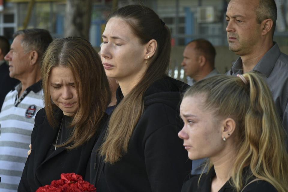 Former schoolmates and friends of two Russian soldiers react with emotion as they attend a ceremony commemorating them at the school where they studied in Saki, Crimea, on Sept. 9, 2022. (AP Photo)