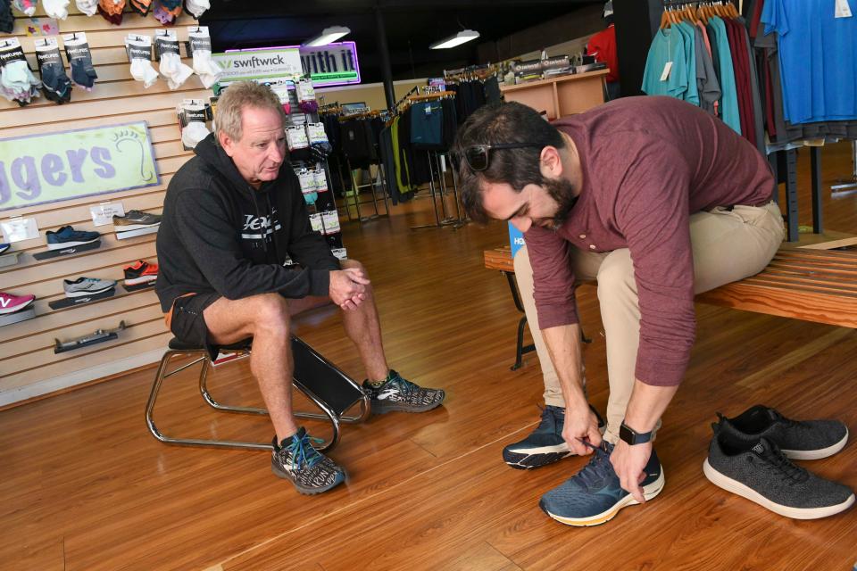Run With It owner Jeff Harris helps customer Aron Altmark with a shoe purchase at the downtown Fort Walton Beach business. Jeff and Donna Harris have been longtime advocates for the local running community, and helped raise money for a rubberized track at Fort Walton Beach High School.