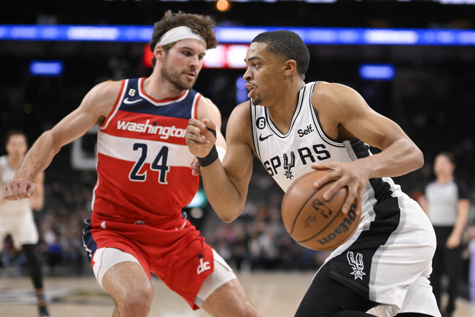 San Antonio Spurs' Keldon Johnson, right, drives against Washington Wizards' Corey Kispert during the first half of an NBA basketball game, Monday, Jan. 30, 2023, in San Antonio. (AP Photo/Darren Abate)