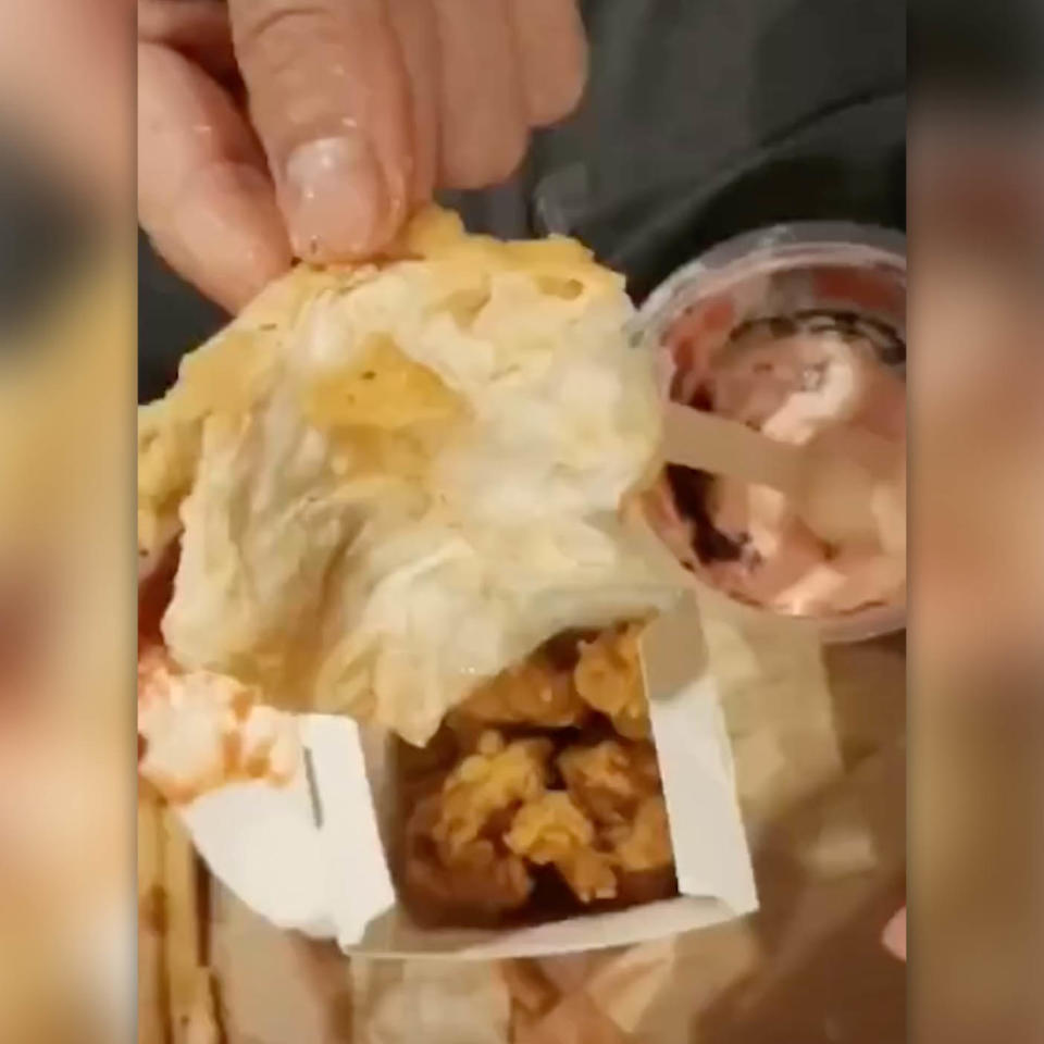 Pictured is a woman's KFC meal with a hand holding up deep-fried toilet paper.