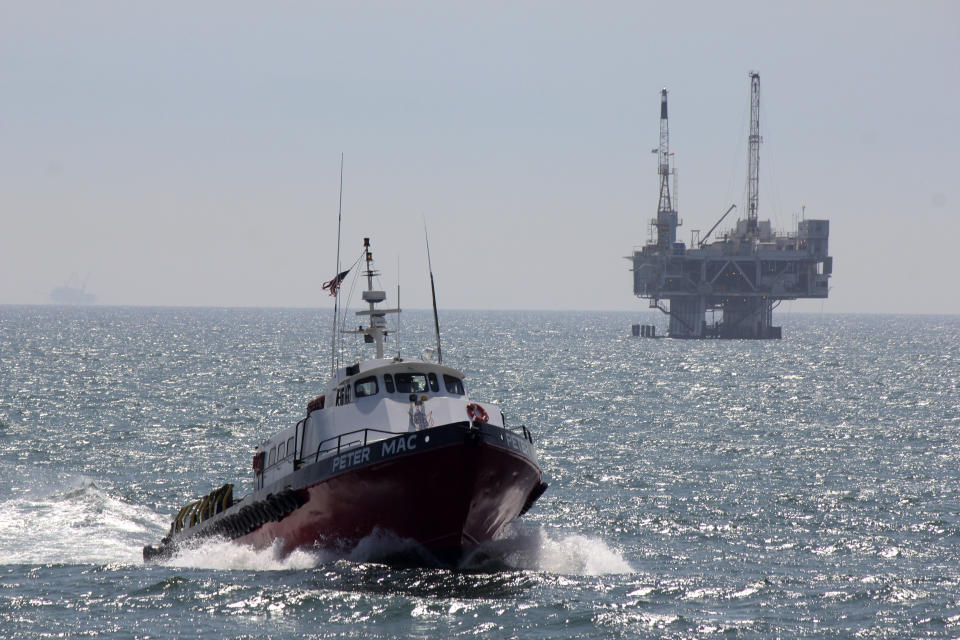 FILE - This May 16, 2015, file photo shows a service boat carrying workers back to shore from a platform off Seal Beach, Calif. A proposal to replace a pipeline near Santa Barbara that was shut down in 2015 after causing California's worst coastal oil spill in 25 years is inching through a government review, even as the state moves toward banning gas-powered vehicles and oil drilling. (AP Photo/John Antczak, File)
