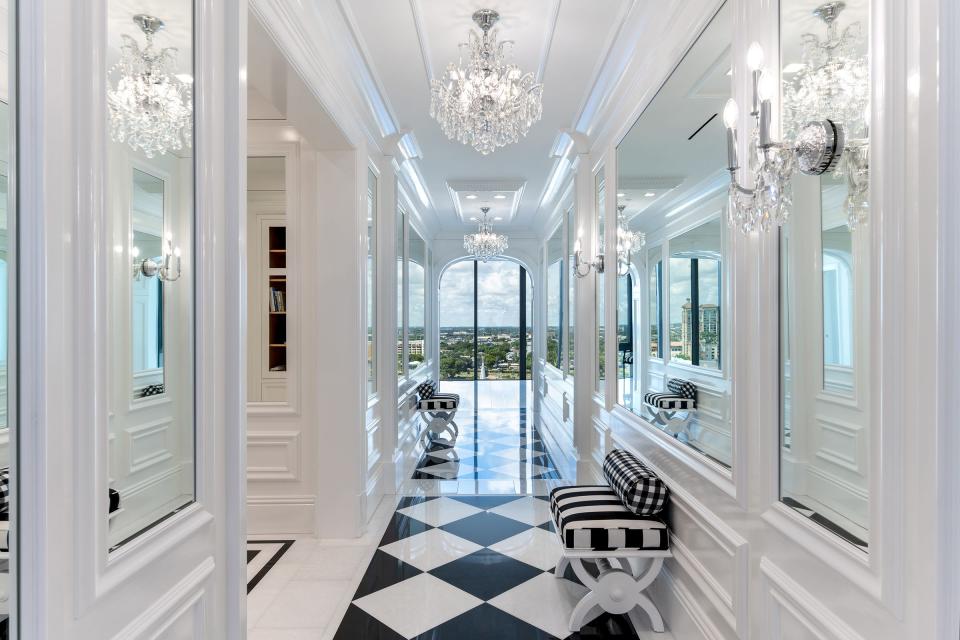 Seen from the dining room, the mirrored gallery has a black-and-white-marble checkerboard floor. At the far end is a window in the family room, which views West Palm Beach.