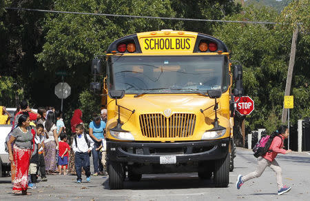 Students disembark from a school bus outside The Ivy Apartments, where a man diagnosed with the Ebola virus was staying in Dallas, Texas October 1, 2014. REUTERS/Mike Stone