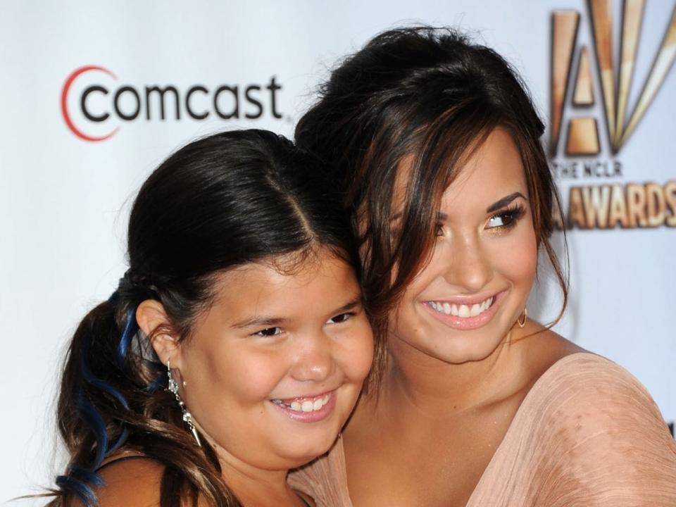 A young Madison in a dress next to Demi on a red carpet.