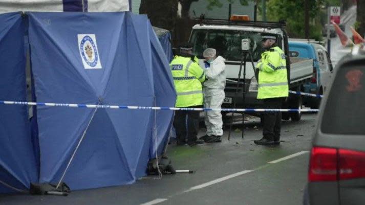 Police tent in the foreground with police officers and forensics staff in the background