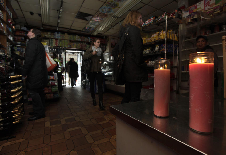 People shop in a candle-lit deli in New York's Tribeca neighborhood, Wednesday, Oct. 31, 2012. In lower Manhattan, some stores are open even though their power is still out. Others are busing essential employees to work. Days after superstorm Sandy hit, businesses both big and small are facing a tough choice, to reopen or stay closed.(AP Photo/Richard Drew)