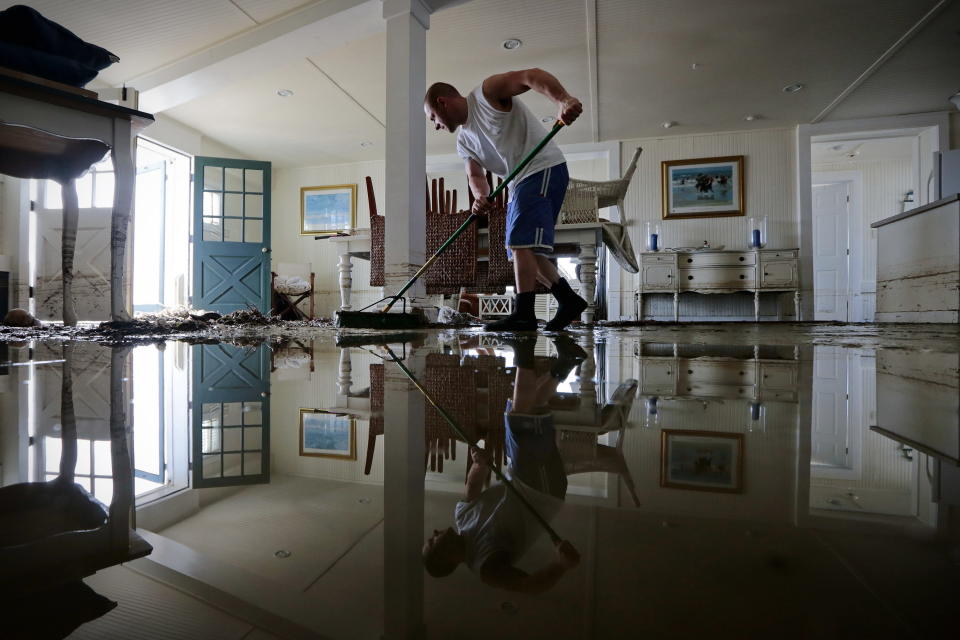 Jason Locke sweeps water and mud from his parents' home in Westport, Mass., Tuesday, Oct. 30, 2012. Many homeowners who suffered losses because of flooding from Hurricane Sandy are likely to find themselves out of luck. Standard homeowners policies don't cover flooding damage, and the vast majority of homeowners don't have flood insurance.Yet it's likely that many Northeasterners will purchase it in coming months, hoping they'll be covered the next time around, at a cost averaging around $600 a year. (AP Photo/The Standard Times, Peter Pereira)