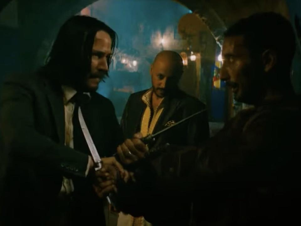 Keanu Reeves as John Wick in a fight in an alleyway.