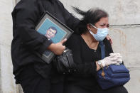 Family members react during the burial of relative at the special section of Jombang cemetery opened to accommodate the surge in deaths during coronavirus outbreak in Tangerang, Indonesia, Tuesday, Jan. 26, 2021. Indonesia has reported more cases of the virus than any other countries in Southeast Asia. (AP Photo/Tatan Syuflana)