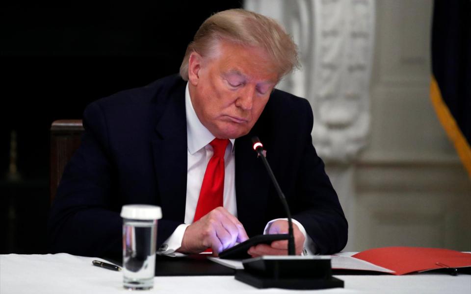 President Donald Trump looks at his phone during a roundtable with governors on the reopening of America's small businesses, in the State Dining Room of the White House, Thursday, June 18, 2020 - Alex Brandon /AP 