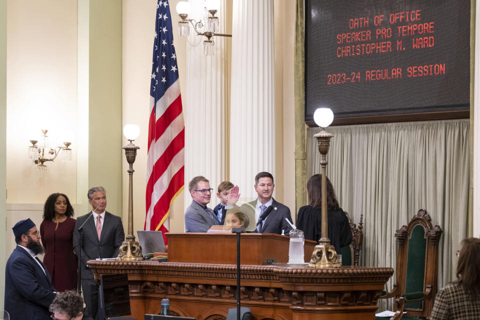 Assembly member Chris Ward, is accompanied by his partner Thom Harpole, and children Betty and Billy as he is sworn in as Speaker Pro Tempore during the opening session of the California Legislature in Sacramento, Calif., on Dec. 5, 2022. Evidence of a transgender person's name or gender marker change could soon be hidden from the public record in California and Washington as state lawmakers are considering new privacy provisions. A California bill introduced in January by Ward would shield minors from such requests by requiring the state to seal any petition filed by a person under 18 for a gender, sex or name change. (AP Photo/José Luis Villegas, Pool)