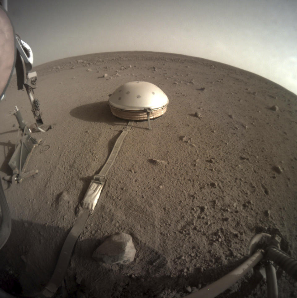 FILE - This Feb. 18, 2020 photo made available by NASA shows the InSight lander's dome-covered seismometer, known as SEIS, on the surface of Mars. The spacecraft is losing power because of all the dust that's accumulated on its solar panels. NASA said Tuesday, May 17, 2022, it will keep using the spacecraft's seismometer to detect marsquakes until its power peters out. Officials expect operations to cease in July, almost four years after InSight's arrival at Mars. (NASA/JPL-Caltech via AP, File)