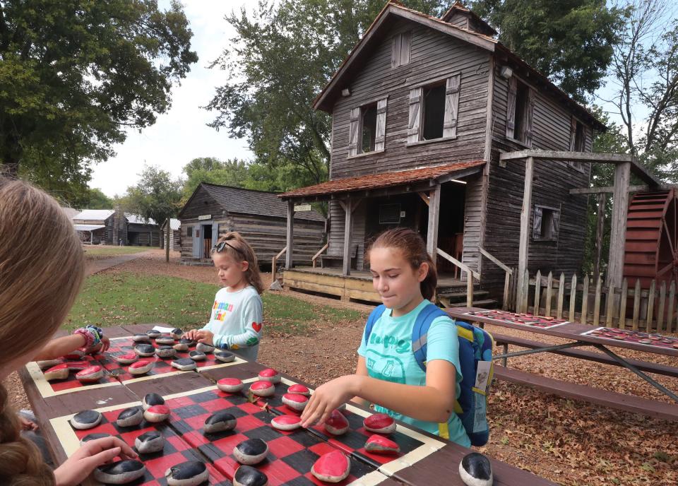 Sisters Isabella, 8, in the background and Olivia Booker, 11, foreground play checkers with their other sisters Breanna and Gabby Booker, 13, as they take a home school field trip to Cannonsburgh Village on Thursday, Sept. 7, 2023. Laura Booker the mother of the girls said that they live in Tullahoma said it was hard to find a place to take her home schooled kids to show Tennessee history and was thankful to find Cannonsburgh Village. Linda Booker and her husband Adam Booker were also please to find the village free to visit.