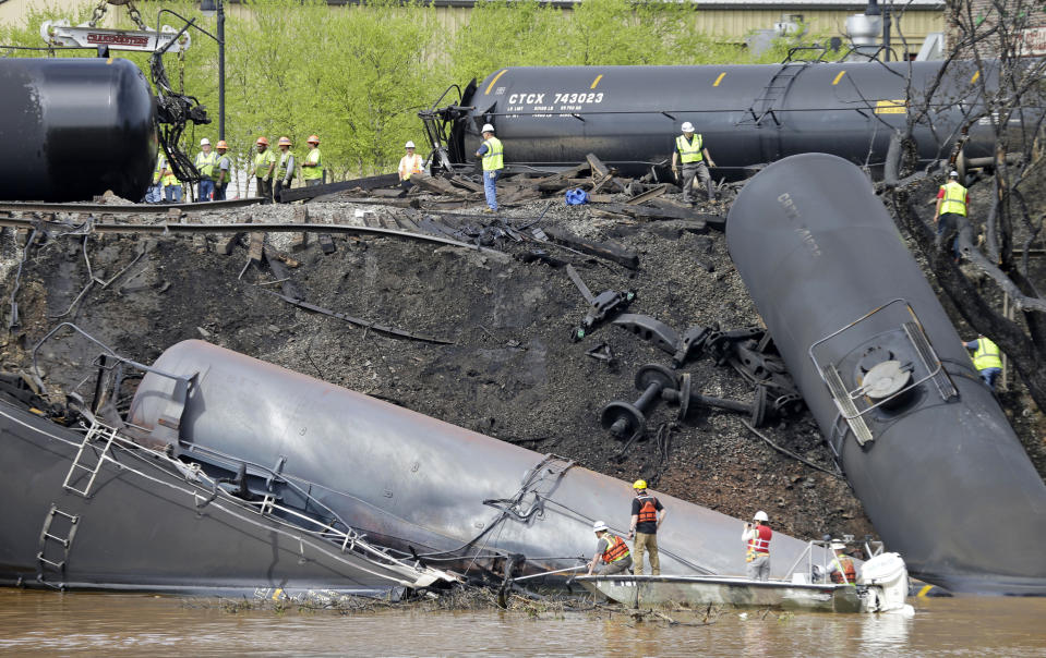 FILE - In this May 1, 2014, file photo survey crews in boats look over tanker cars as workers remove damaged tanker cars along the tracks where several CSX tanker cars carrying crude oil derailed and caught fire along the James River near downtown Lynchburg, Va. Inspectors have found almost 24,000 safety defects over a two-year period along United States railroad routes used to ship volatile crude oil. Data obtained by The Associated Press shows many of the defects were similar to problems blamed in past derailments that caused massive fires or oil spills in Oregon, Virginia and Montana. (AP Photo/Steve Helber, File)