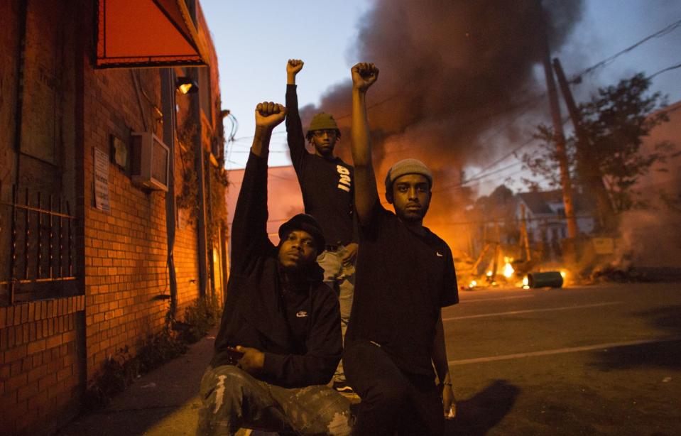 Protesters raise fists in front of a burning car in Minneapolis in response to the death of George Floyd.