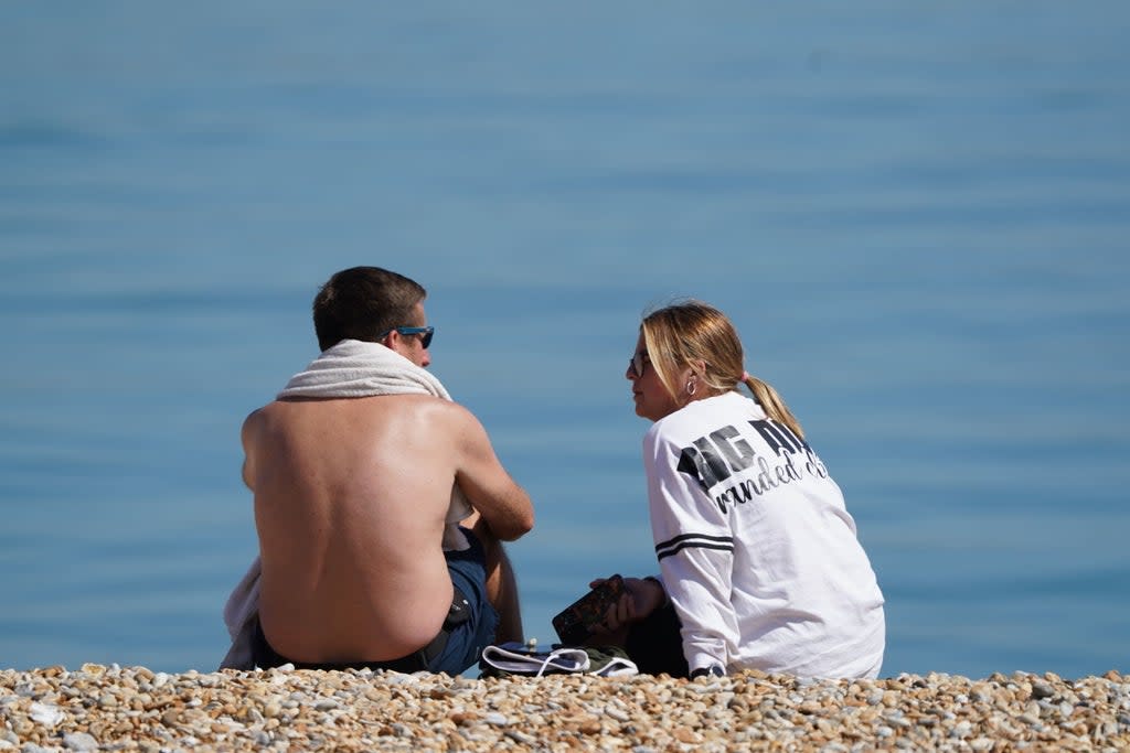 A man and woman enjoying the warm weather on a beach near Dover  (PA)