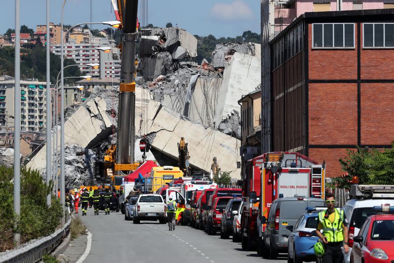 FILE PHOTO: Firefighters and rescue workers stand at the site of a collapsed Morandi Bridge in the port city of Genoa