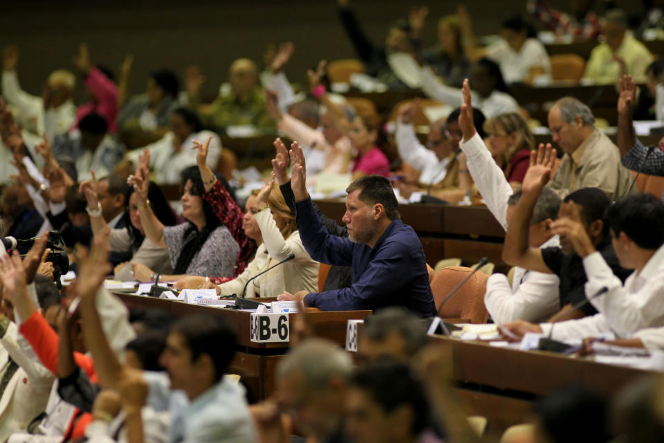 Members of the National Assembly raise their hands to vote during an extraordinary session overhauling their foreign investment law at the National Assembly in Havana, Cuba, Saturday, March. 29, 2014. Cuban lawmakers approved a law Saturday that aims to make it more attractive for foreign investors to do business in and with the country, a measure seen as vital if the island's struggling economy is to improve. (AP Photo/Cubadebate, Ismael Francisco)