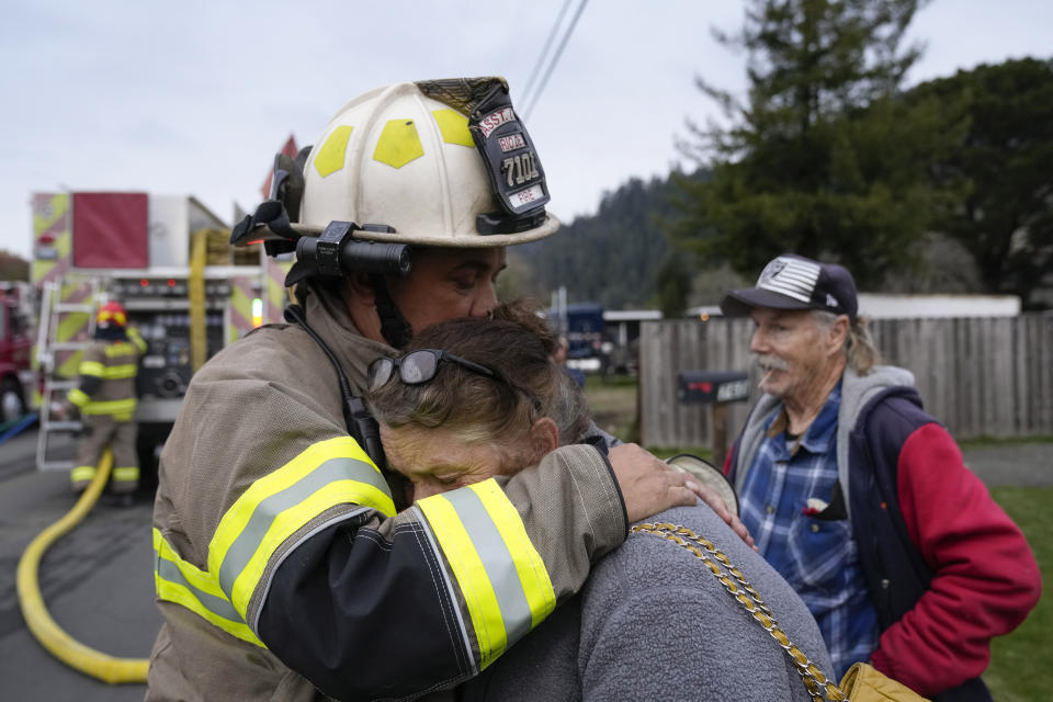 Rio Dell assistant fire chief Ryan Heussler, left, hugs Patty, who did not wish to give her last name, as firefighters battled a fire at her home in Rio Dell, Calif., Wednesday, Dec. 21, 2022. (AP Photo/Godofredo A. Vásquez)
