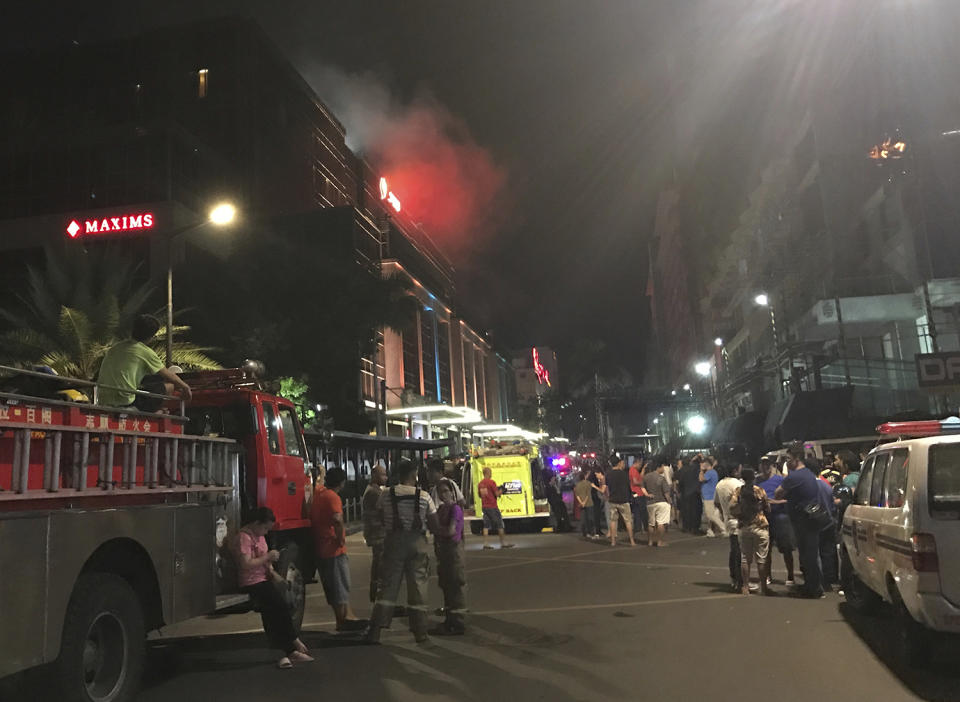 <p>Emergency responders and onlookers gather outside as smoke rises from the Resorts World Manila complex, early Friday, June 2, 2017, in Manila, Philippines. (Photo: Bullit Marquez/AP) </p>