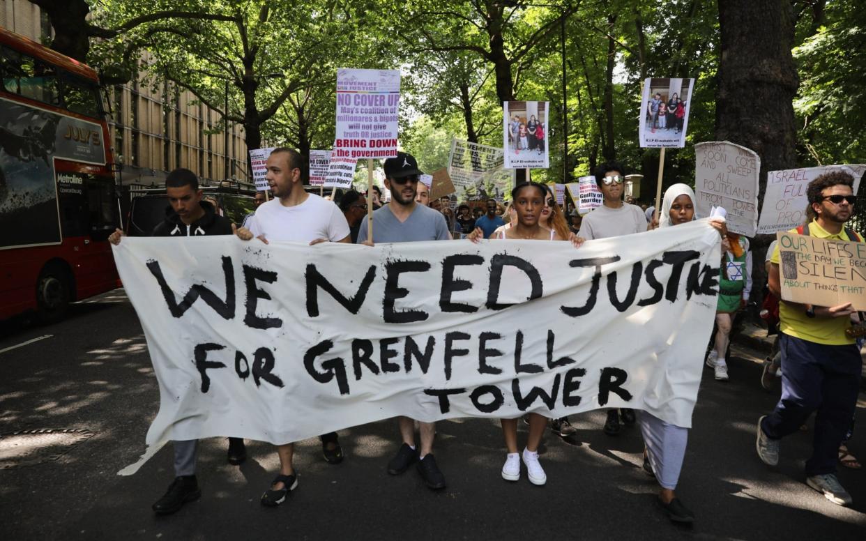 Protesters hold signs calling for justice for the victims of the Grenfell Disaster - Getty Images Europe