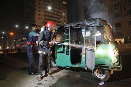 A firefighter and a policeman extinguish a fire on an auto rickshaw in Dhaka November 25, 2013. REUTERS/Andrew Biraj