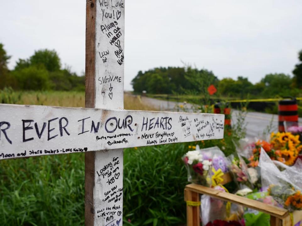 People left flowers and signed a cross in memory of Curtis King, River Wells, Jason O'Connor, Luke West, Jersey Mitchell and Haley Marin, who all lost their lives in a car crash over the weekend in Barrie, Ont.  (Paul Smith/CBC - image credit)