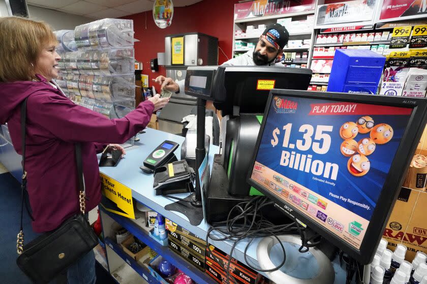 A Mega Million sign displays the estimated jackpot of $1.35 Billion as a customer purchases her Mega Millions ticket at the Cranberry Super Mini Mart in Cranberry, Pa., Thursday, Jan. 12, 2023. After twenty-five consecutive drawings with no grand prize winner named, the Mega Millions jackpot is now $1.35 billion, making it one of the largest jackpots in lottery history. (AP Photo/Gene J. Puskar)