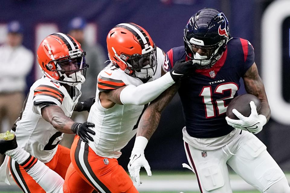 Houston Texans wide receiver Nico Collins is tackled by Cleveland Browns safety Juan Thornhill (1) and cornerback Denzel Ward during a wild-card playoff game Saturday in Houston.