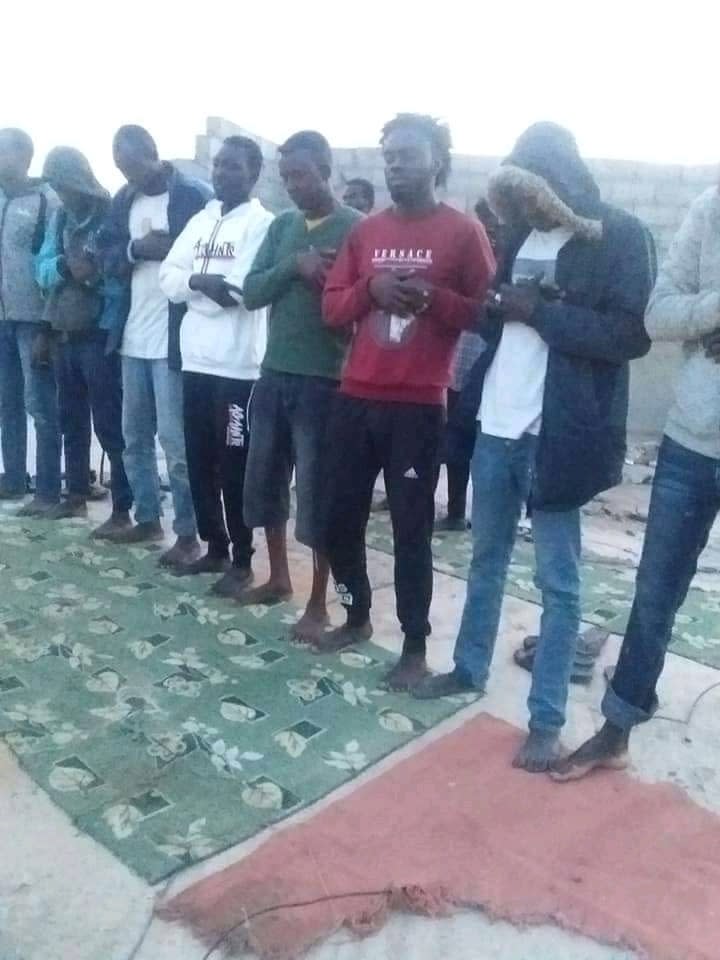 Foto suministrada por la familia de Mubarak Jaber en la que el joven sudanés aparece junto a otro migrantes rezando antes de subierse a una precaria embarcación para tratar de llegar de Libia a Europa el 20 de abril del 2021. El bote se quedó sin combustible y se hundió. Se cree que más de 100 migrantes fallecieron. (Foto familiar vía AP)