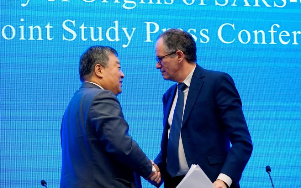 Peter Ben Embarek, a member of the World Health Organization (WHO) team tasked with investigating the origins of the coronavirus disease, shaking hands with Liang Wannian, head of an expert panel on the WHO's Covid response - Aly Song/Reuters