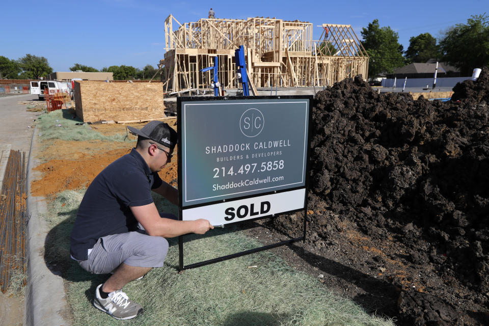 J.R. Molina installs a sold sign in front of a new home lot as construction on a new build continues in the background, seen in Richardson, Texas. (Credit: Tony Gutierrez, AP Photo)