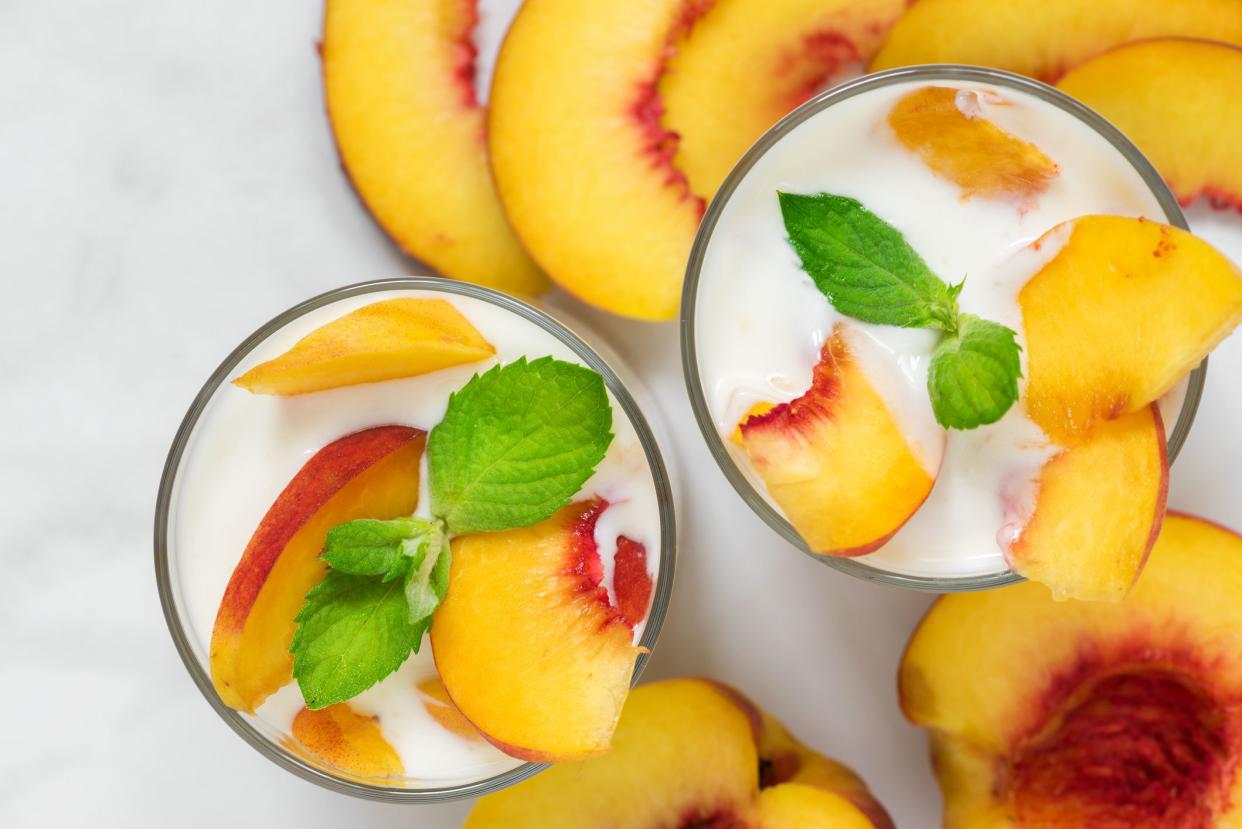 peach yogurt with mint in glasses with fresh fruits on white marble table. healthy breakfast. top view
