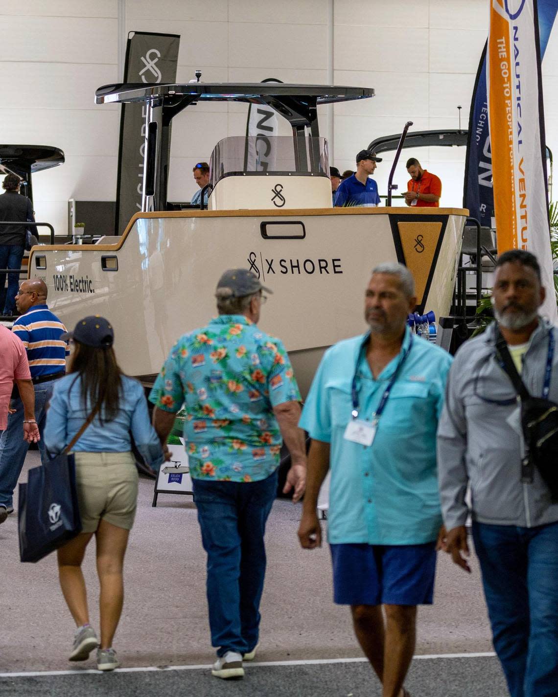 Visitors walk in front of one of the high-end electric boats from Swedish manufacturer X-Shore on display at the Miami International Boat Show.