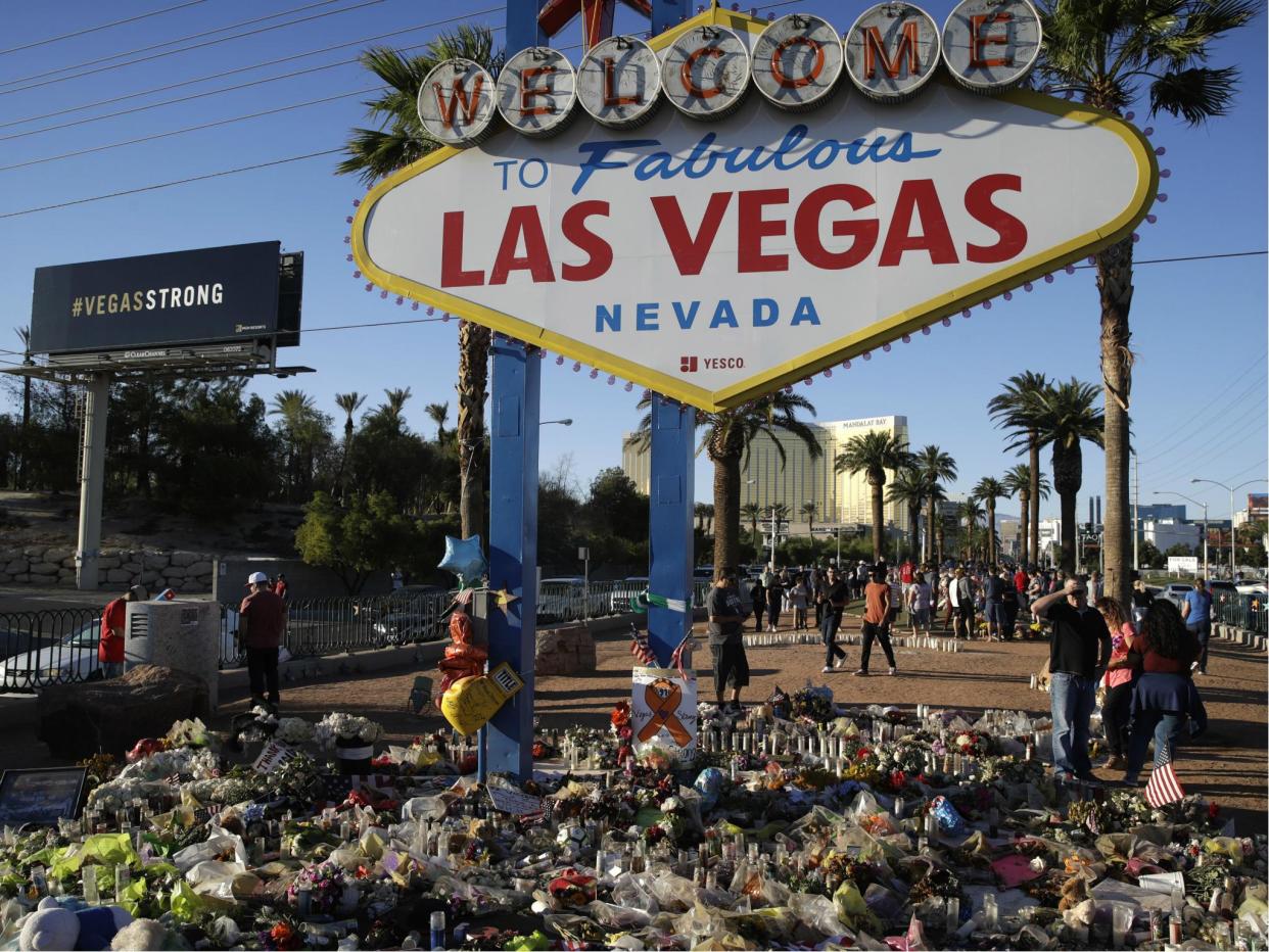 Flowers, candles and other items surround the famous Las Vegas sign at a makeshift memorial for victims of the mass shooting: AP Photo/John Locher