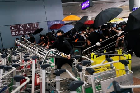 Anti-extradition bill protesters use trolleys and barrier to block the entrance of the airport in Hong Kong