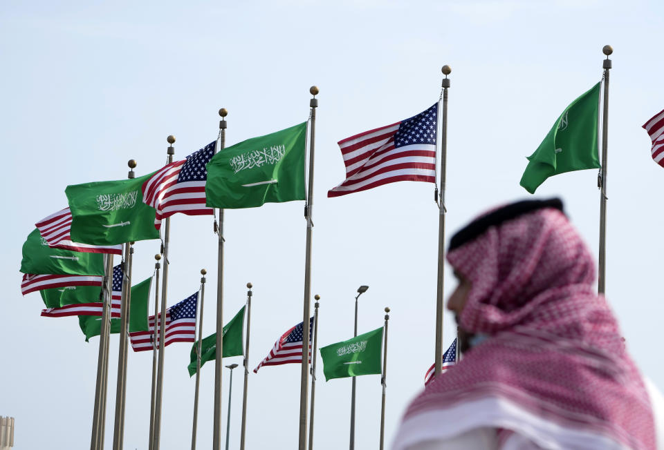 A man stands under American and Saudi Arabian flags prior to a visit by U. S. President Joe Biden, at a square in Jeddah, Saudi Arabia, Thursday, July 14, 2022. (AP Photo/Amr Nabil)