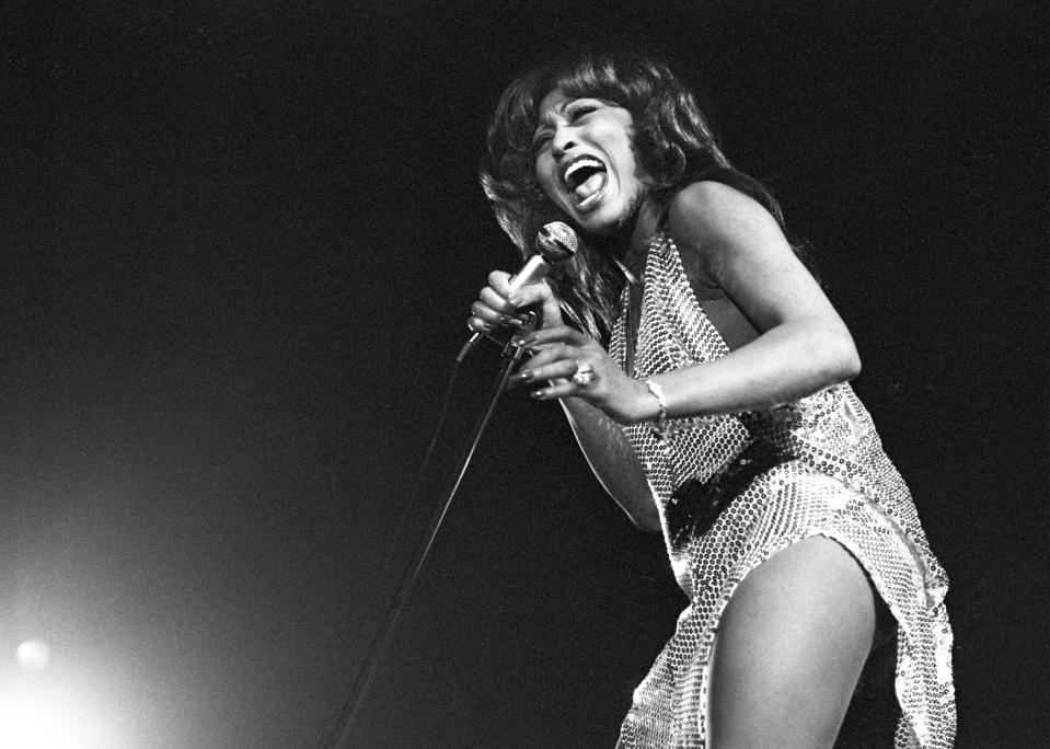Tina Turner holding a microphone and singing