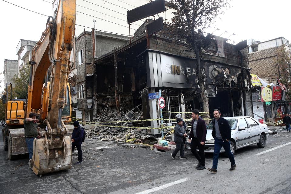 FILE PHOTO: People walk near a burnt bank, after protests against increased fuel prices, in Tehran, Iran November 20, 2019. Nazanin Tabatabaee/WANA (West Asia News Agency) via REUTERS 