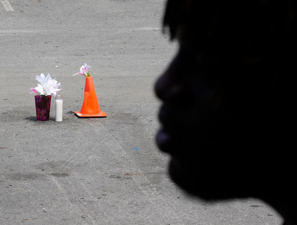 A 17-year-old is silhouetted against the parking lot where a memorial is set up for a fatal shooting that occurred on June 18.