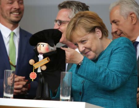 German Chancellor Angela Merkel, a top candidate of the Christian Democratic Union Party (CDU), holds puppet depicting Martin Luther at the election rally in Annaberg-Buchholz, Germany August 17, 2017, ahead of the upcoming federal election. REUTERS/Matthias Schumann