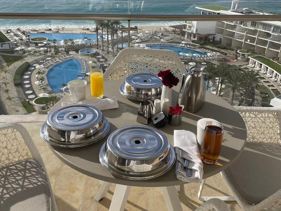 breakfast platters on a table on a balcony overlooking the pool and ocean at an all-inclusive resort
