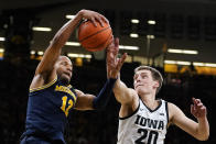 Michigan guard DeVante' Jones (12) grabs a rebound in front of Iowa guard Payton Sandfort (20) during the second half of an NCAA college basketball game, Thursday, Feb. 17, 2022, in Iowa City, Iowa. (AP Photo/Charlie Neibergall)