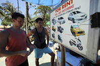 In this March 13, 2014 photo, German tourist Falko Tillwich, left, holds his passport near his German friend, who didn't want to give his name as they try to contact a car rental on Pathong Beach in Phuket province, southern Thailand. Thailand’s sapphire blue waters, wildlife parks, delicious cuisine and raunchy red light districts have attracted tourists for decades. Phuket is one of Thailand’s tourism honeypots. Tourists flock here in droves each year for its sun, sand and laid back ambience. And some lose their passports along the way. (AP Photo/Sakchai Lalit)